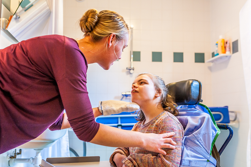 Girl sitting in a chair looking up at a member of her support team